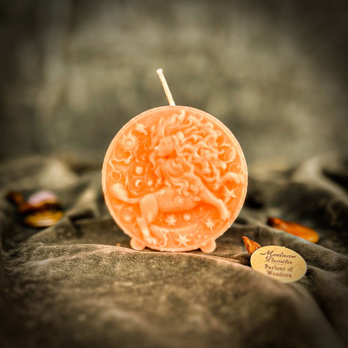 Leo Lion zodiac spell candle in soft pink on draped gray fabric