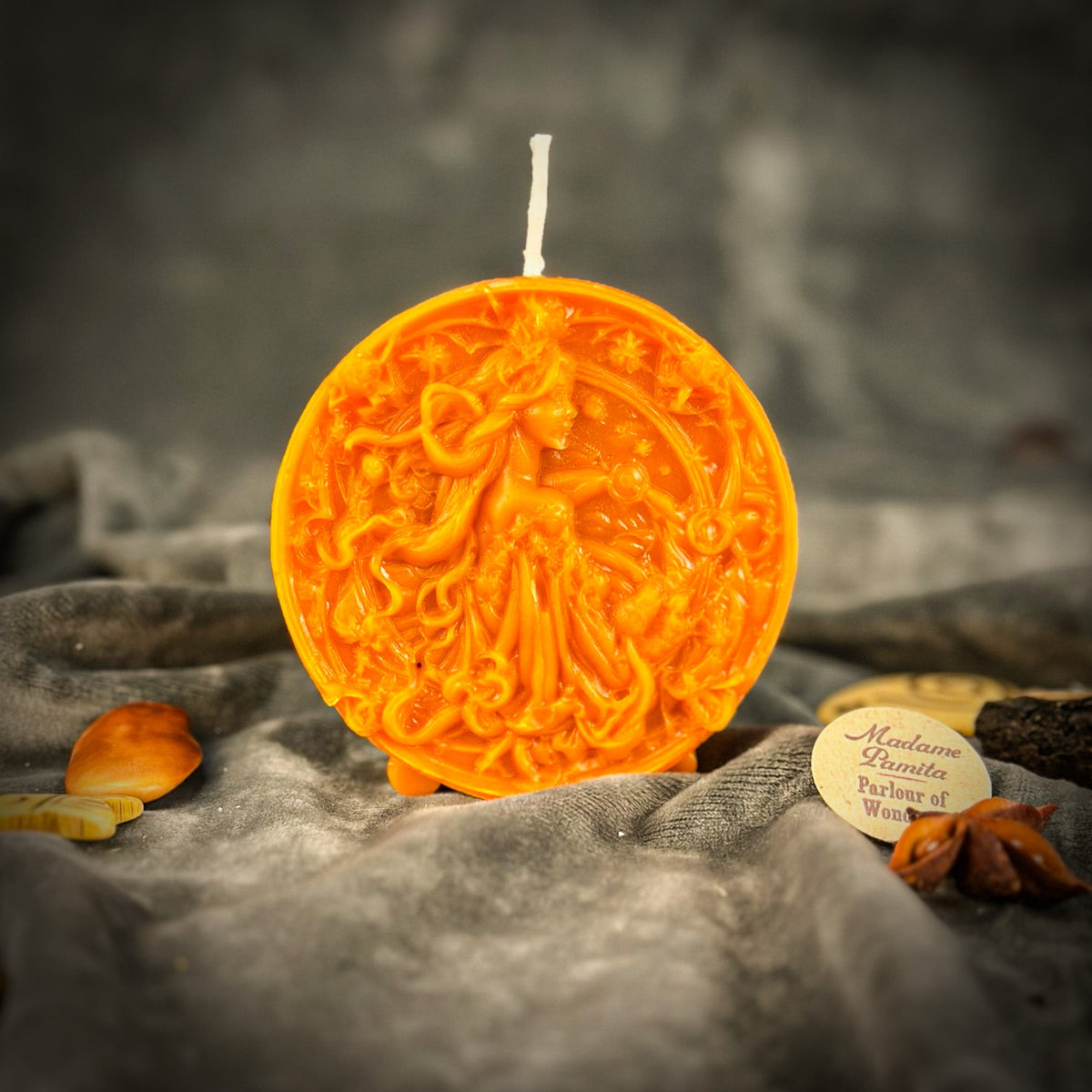 Libra Scales zodiac spell candle in orange on draped gray fabric
