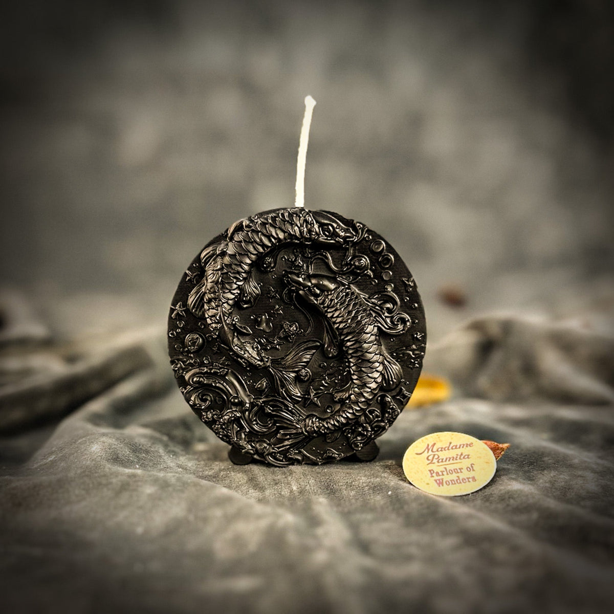 Black Pisces medallion candle, the two fish showing as highlights on dark wax.