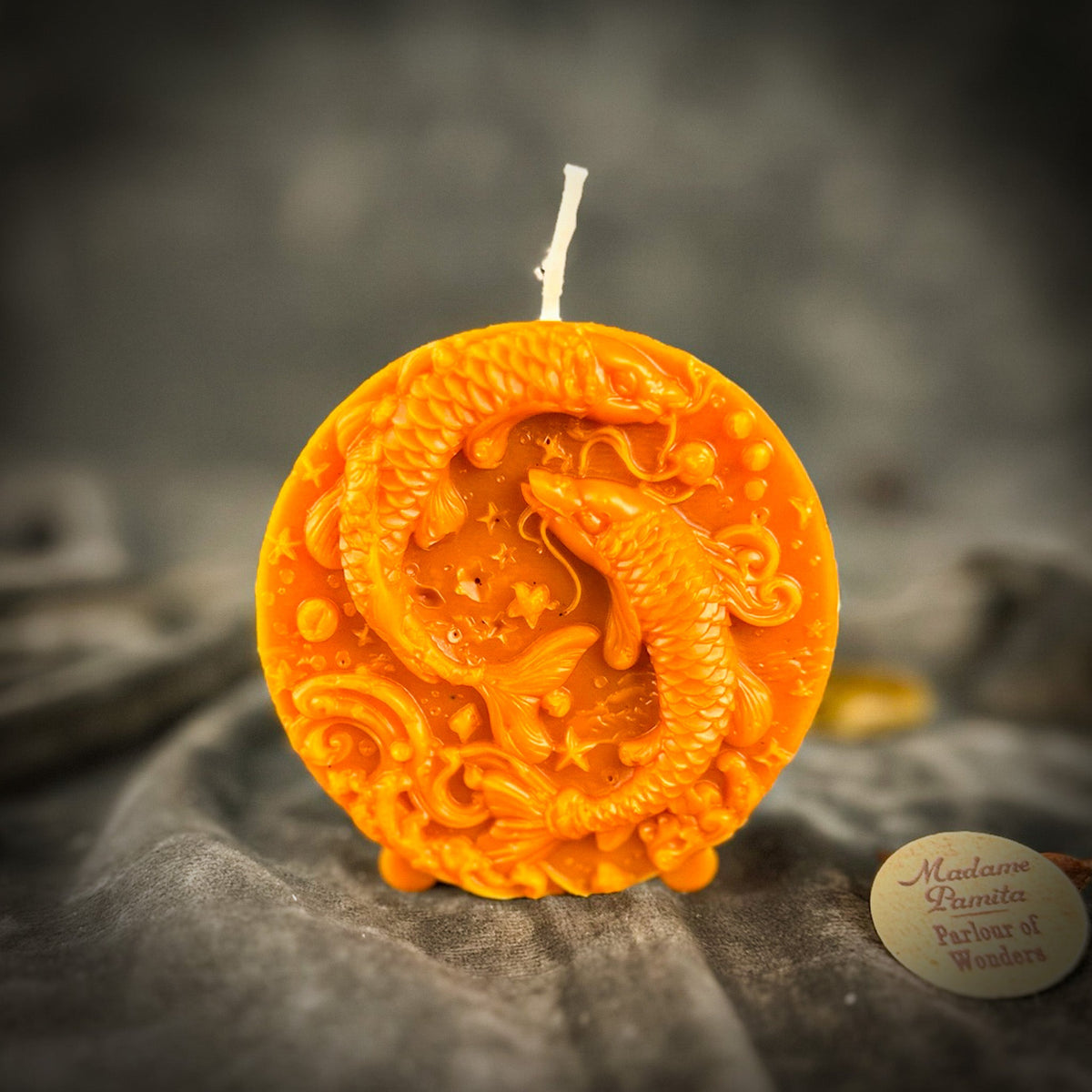 Orange Pisces medallion candle, the raised stars between the fish clearly visible.