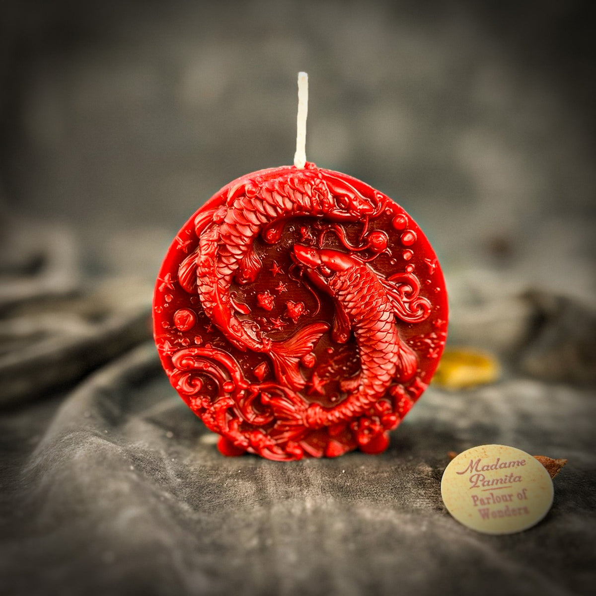 Red Pisces medallion candle, the fish and waves deeply cut.