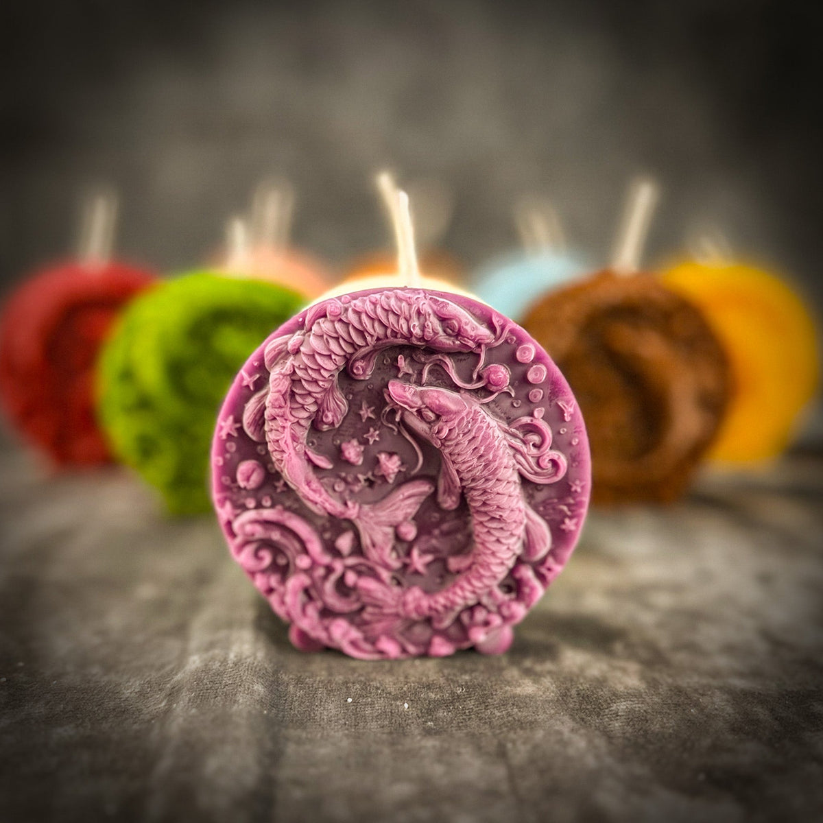 The mauve Pisces medallion in front of the other colors on gray stone, the two fish in sharp relief.