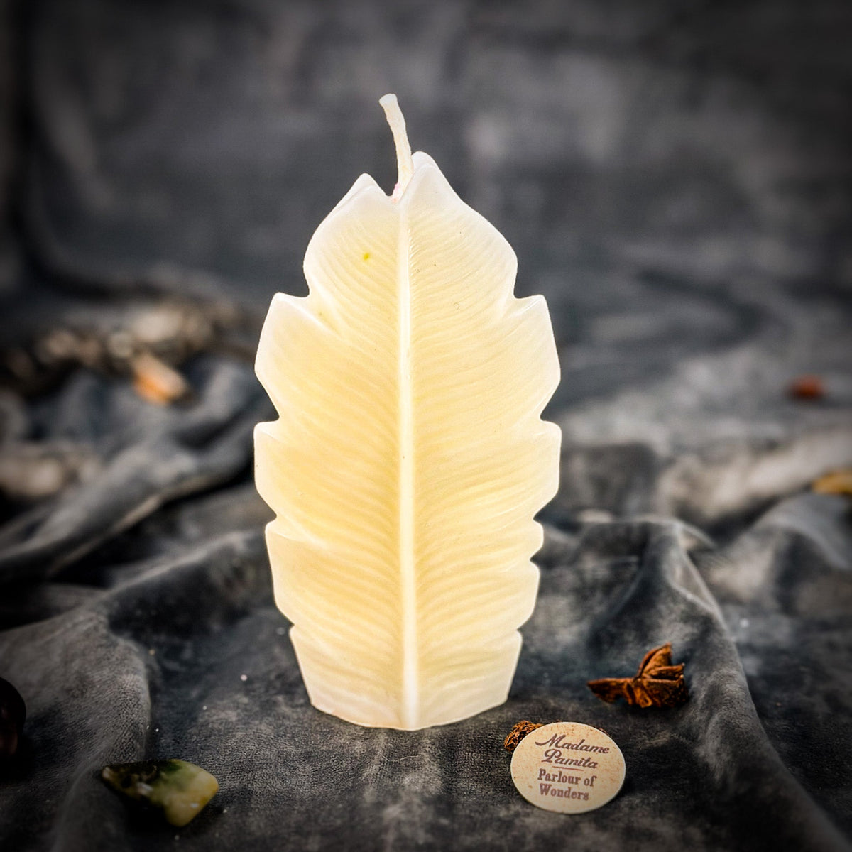 Cream leaf-shaped candle standing upright on gray velvet, the central rib and veins molded into the wax
