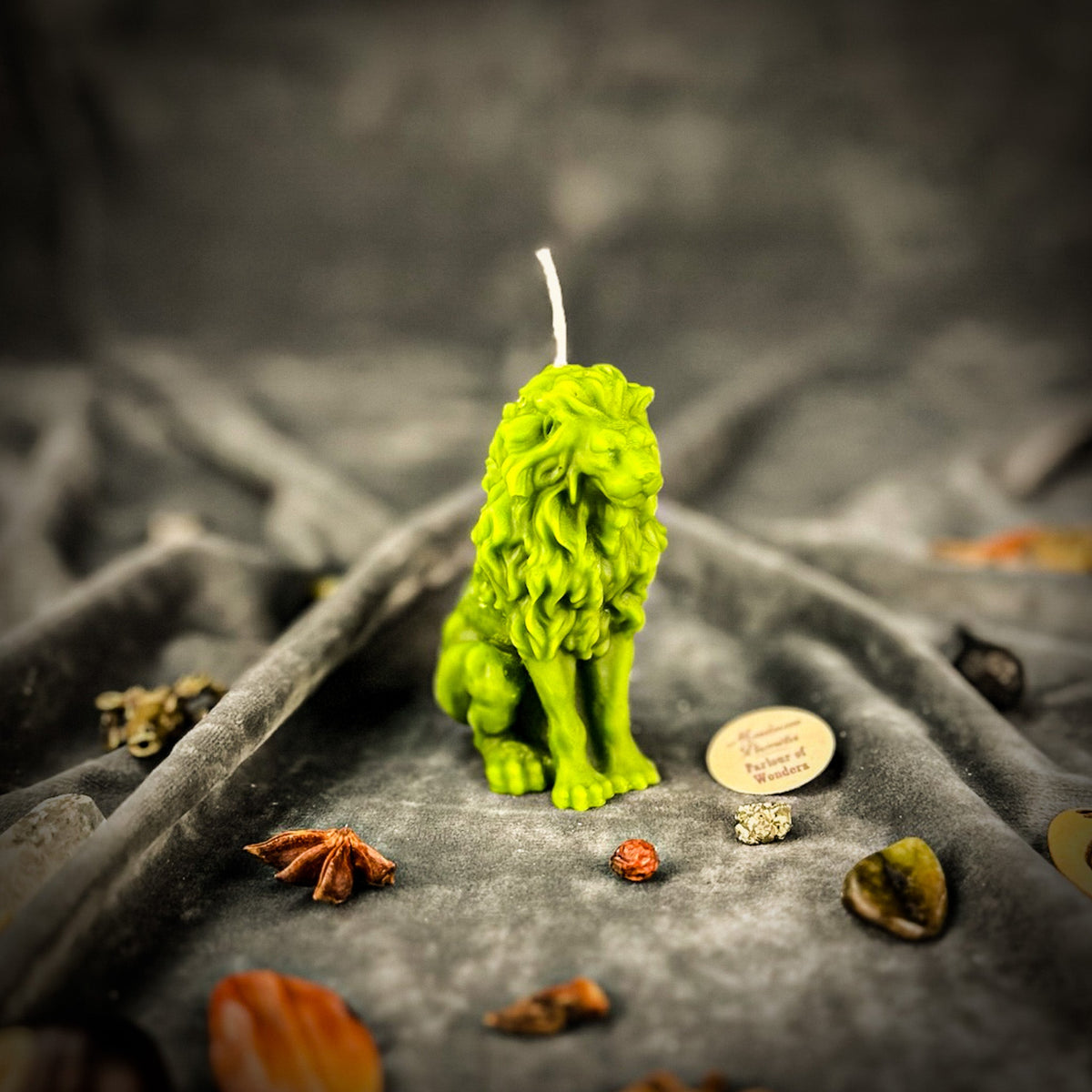 Proud Lion beeswax candle in green on draped gray fabric