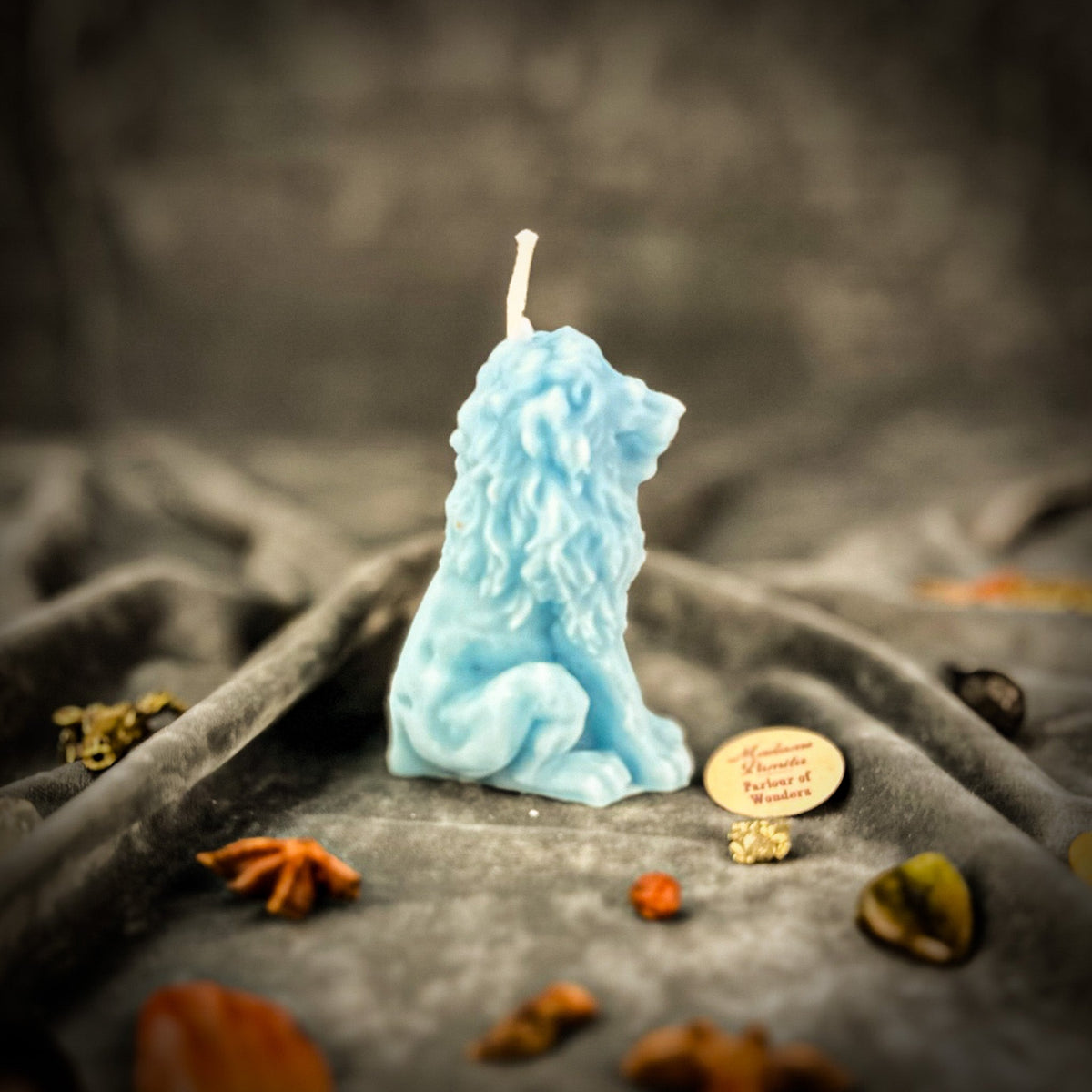 Proud Lion beeswax candle in blue on draped gray fabric