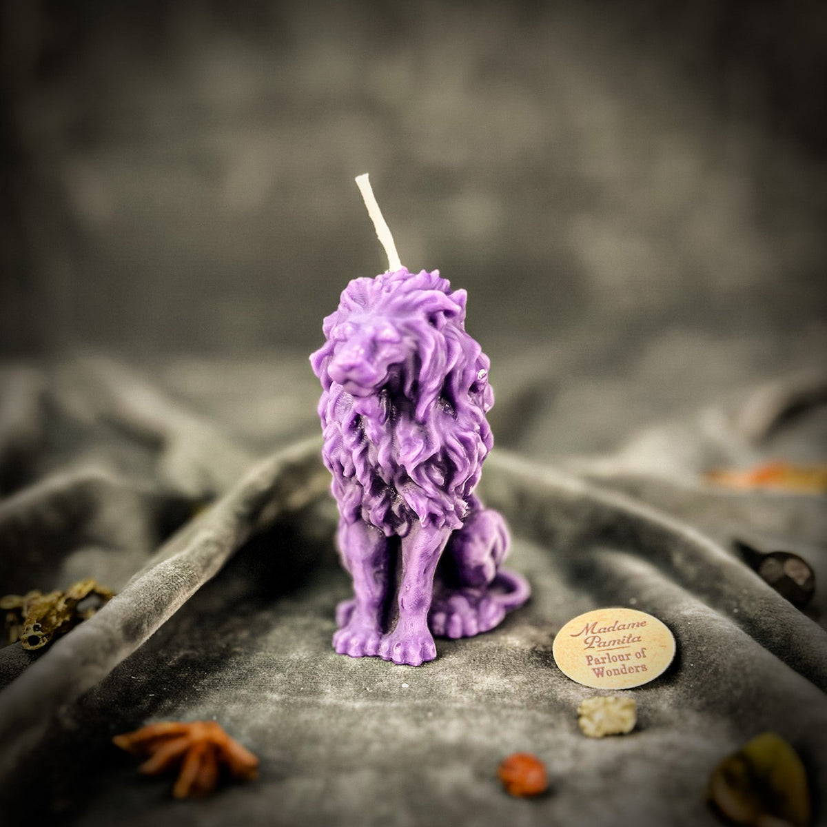 Proud Lion beeswax candle in purple on draped gray fabric