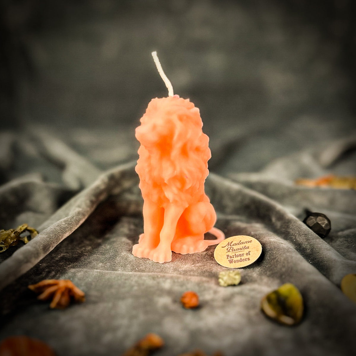 Proud Lion beeswax candle in pink on draped gray fabric