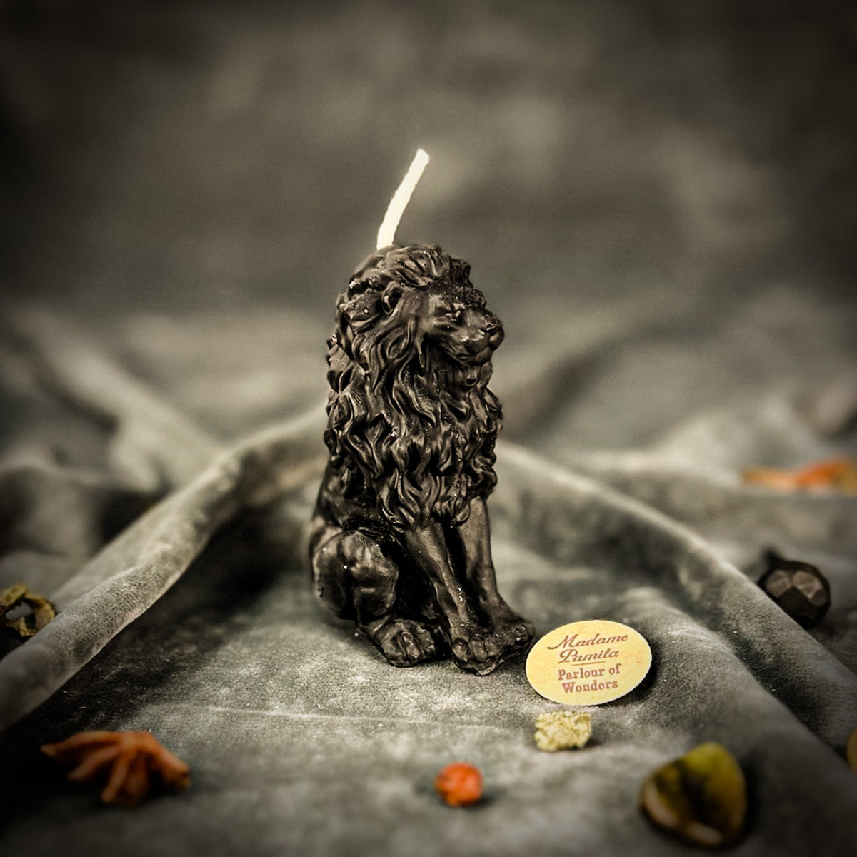 Proud Lion beeswax candle in black on draped gray fabric