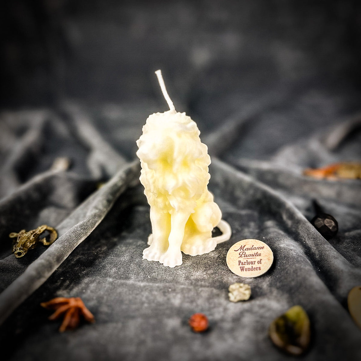 Proud Lion beeswax candle in ivory white on draped gray fabric