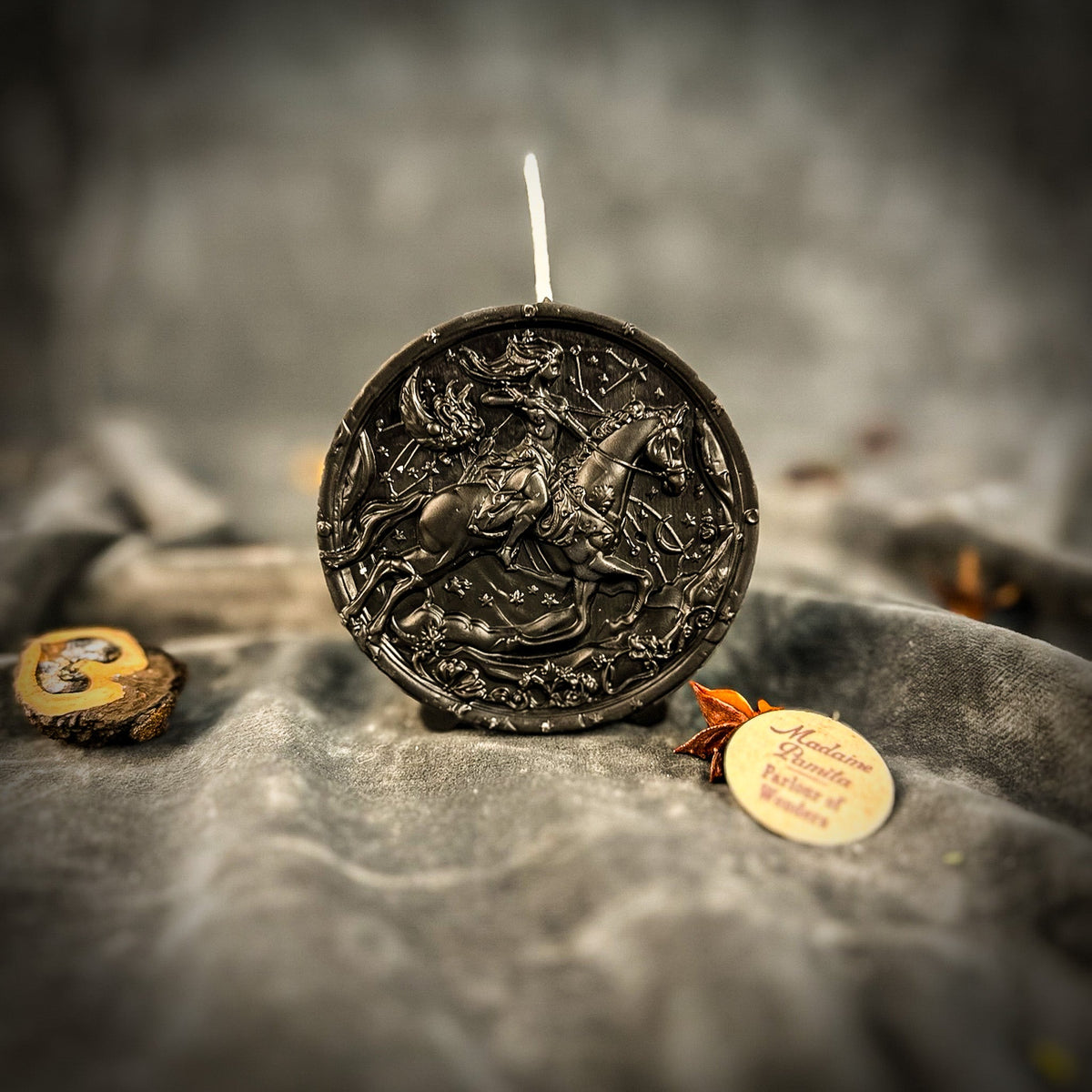 Sagittarius Archer zodiac spell candle in black on draped gray fabric