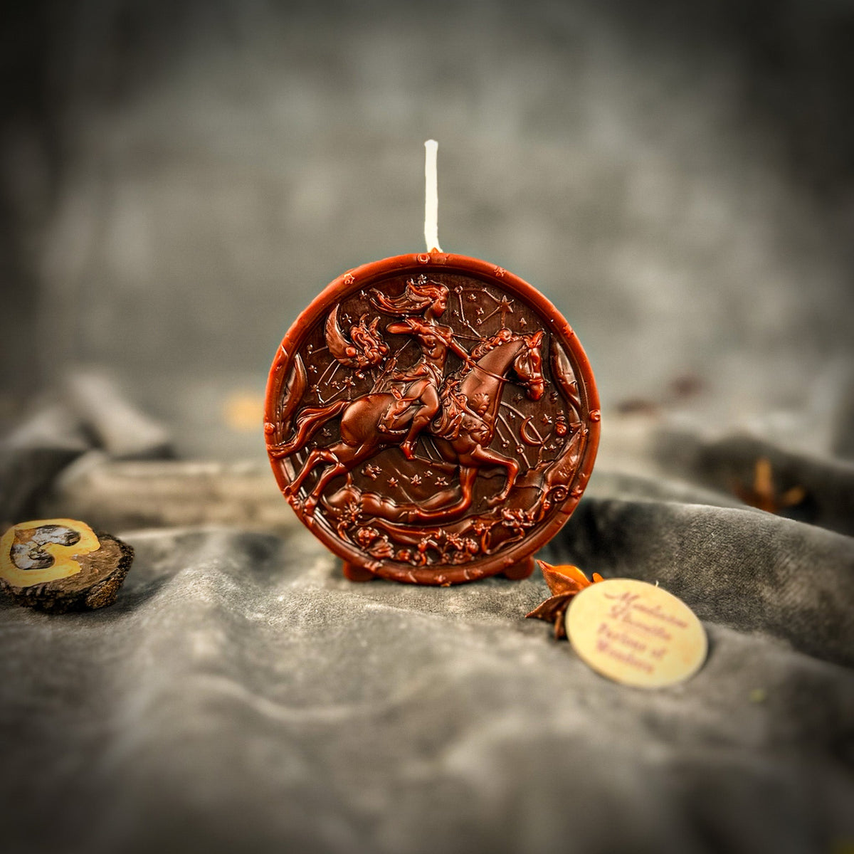 Sagittarius Archer zodiac spell candle in brown on draped gray fabric