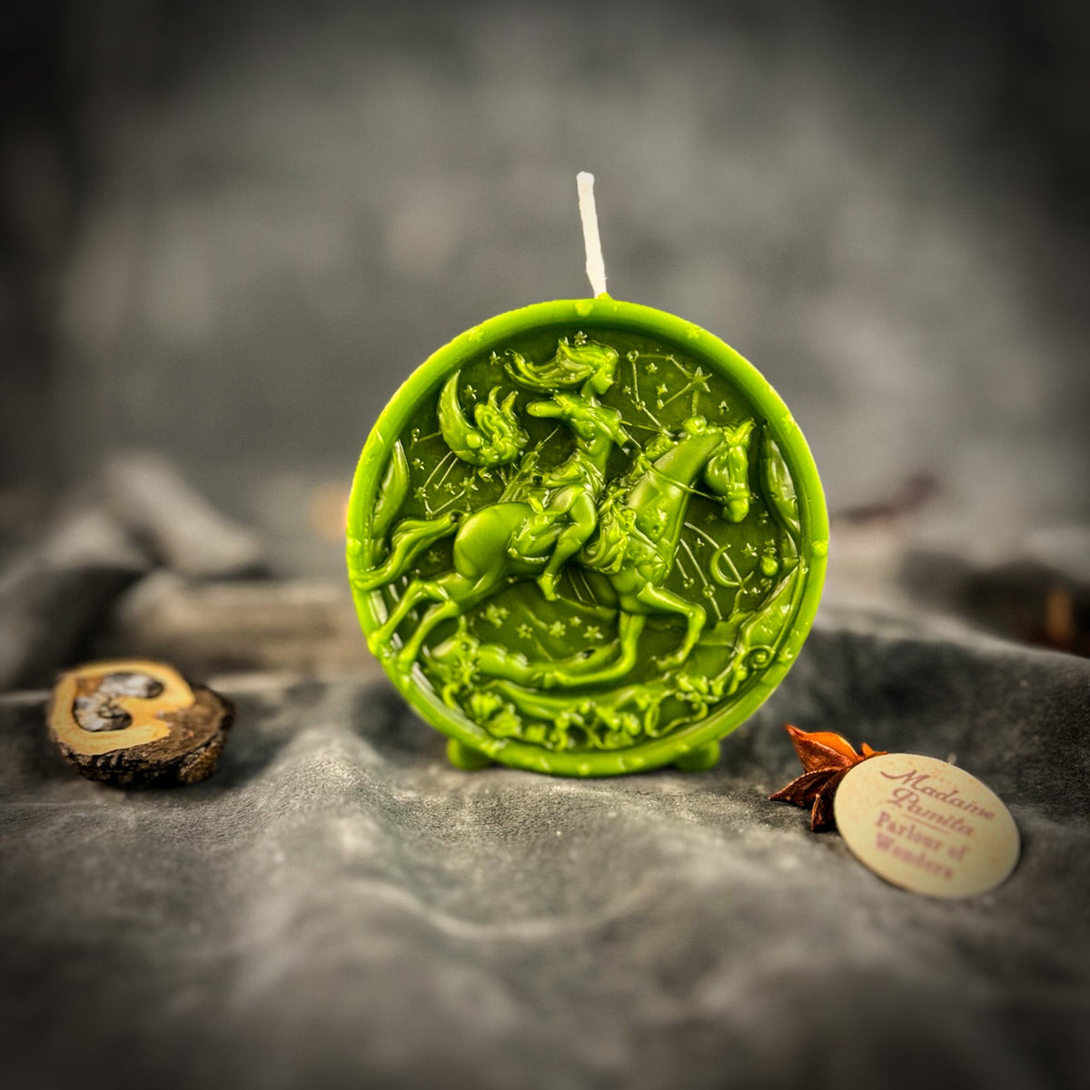 Sagittarius Archer zodiac spell candle in green on draped gray fabric