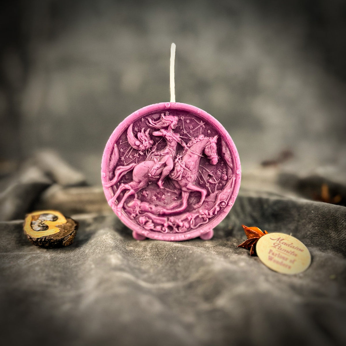 Sagittarius Archer zodiac spell candle in purple on draped gray fabric