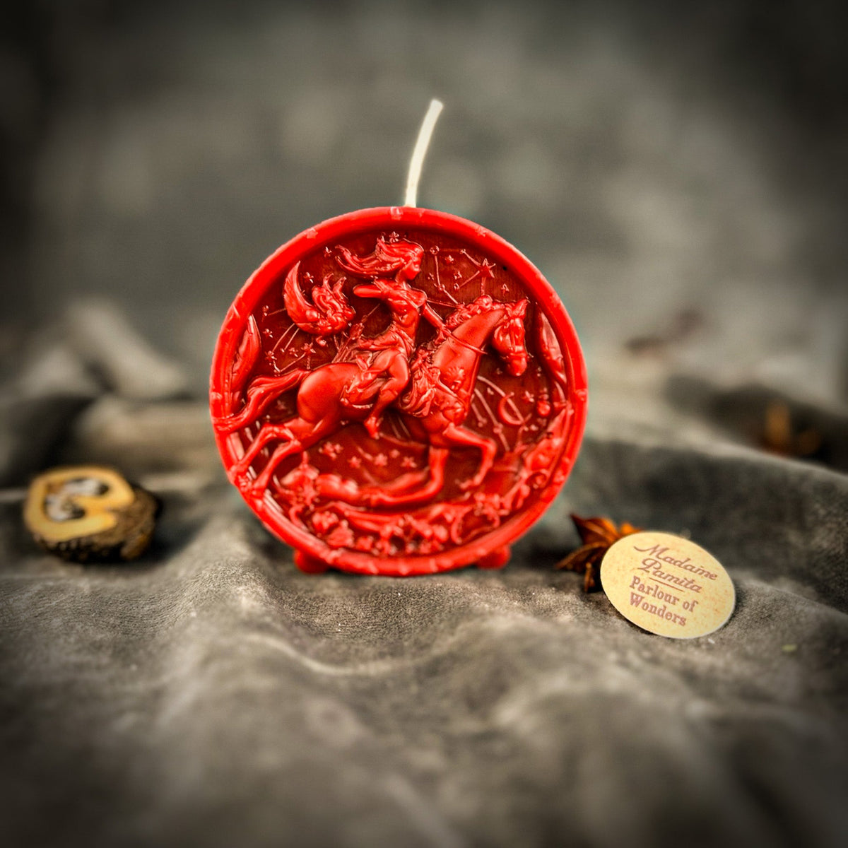 Sagittarius Archer zodiac spell candle in red on draped gray fabric