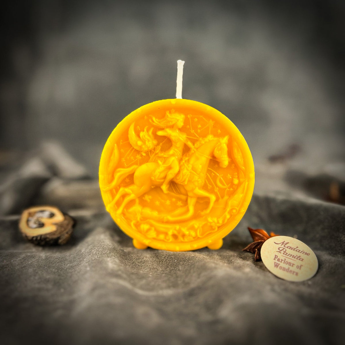Sagittarius Archer zodiac spell candle in yellow on draped gray fabric