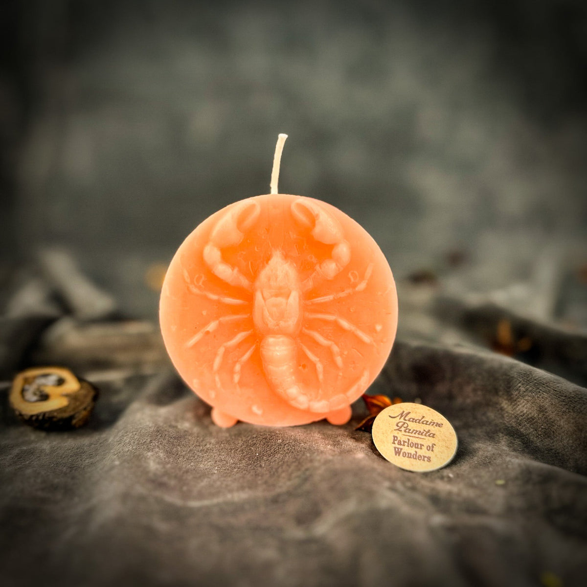 Peach Scorpio medallion candle, the relief softened by the paler wax.