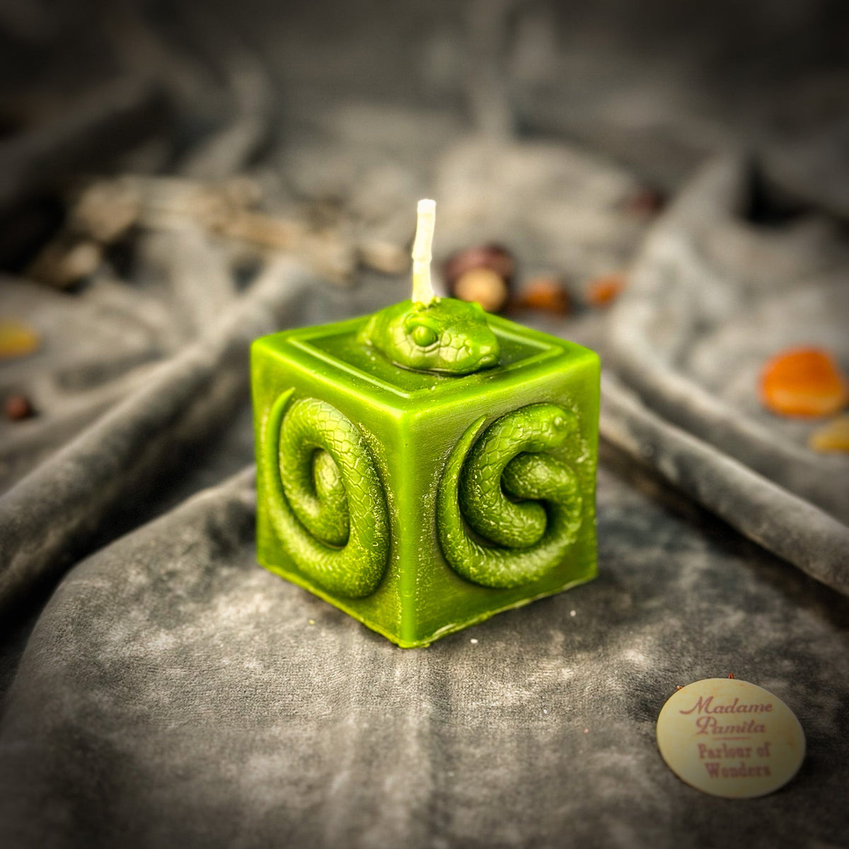 Snake of Transformation beeswax cube candle in green on draped gray fabric