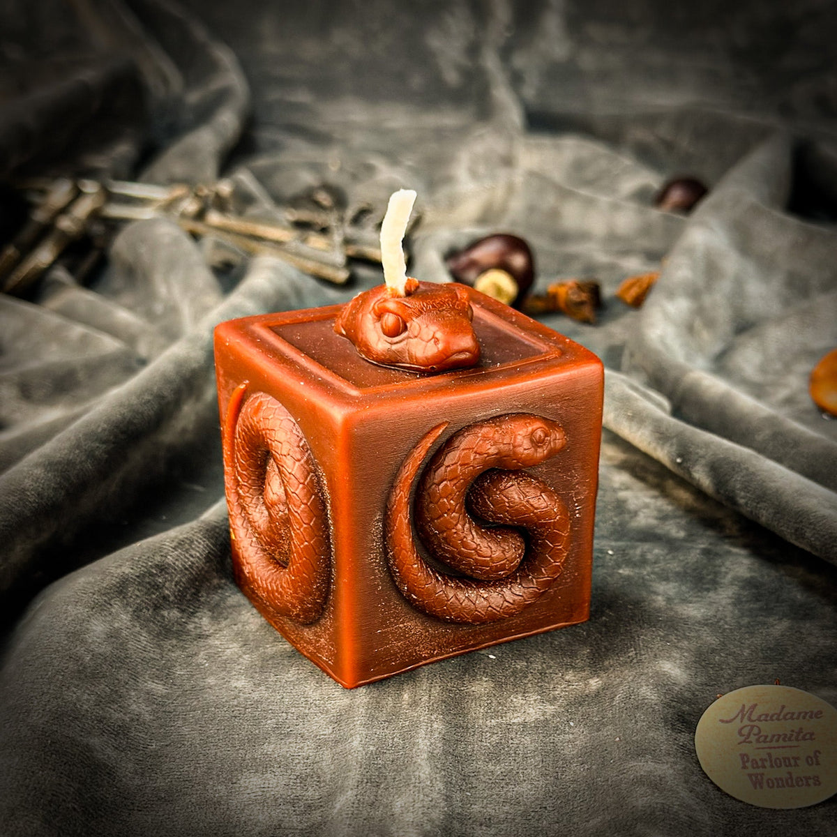 Snake of Transformation beeswax cube candle in brown on draped gray fabric