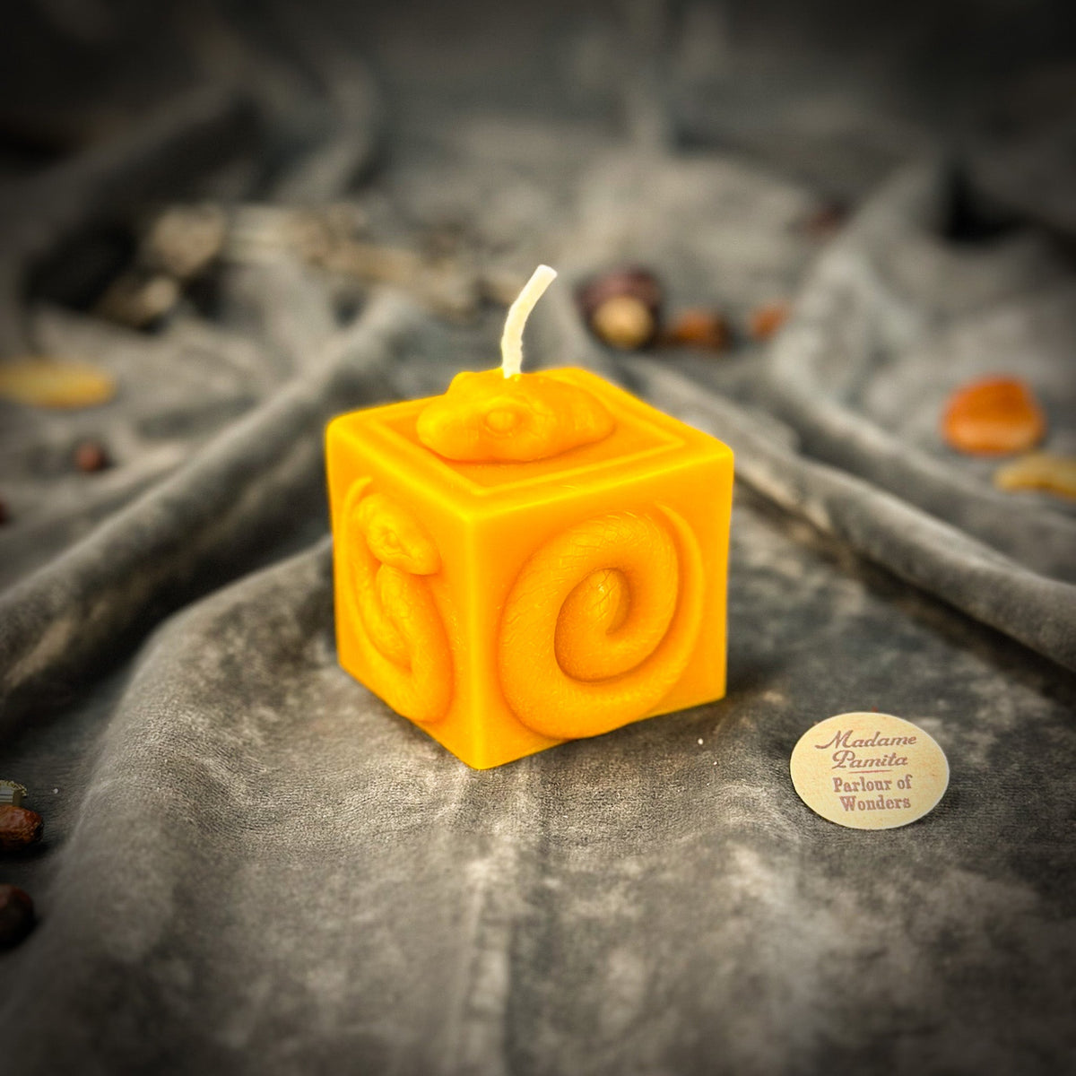 Snake of Transformation beeswax cube candle in yellow on draped gray fabric