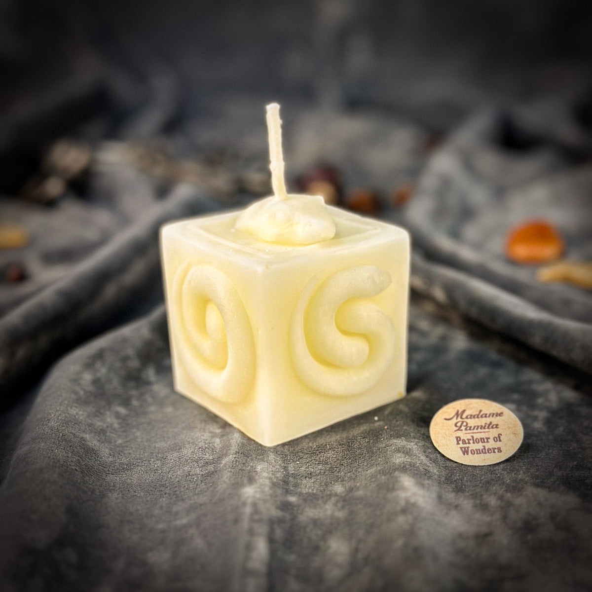 Snake of Transformation beeswax cube candle in ivory white on draped gray fabric