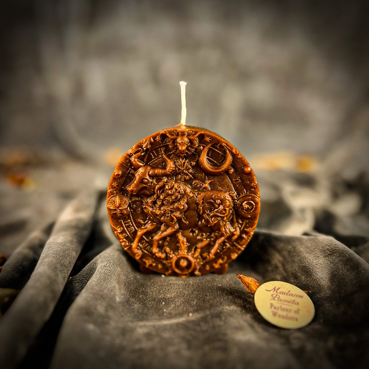 Taurus Bull zodiac spell candle in brown on draped gray fabric