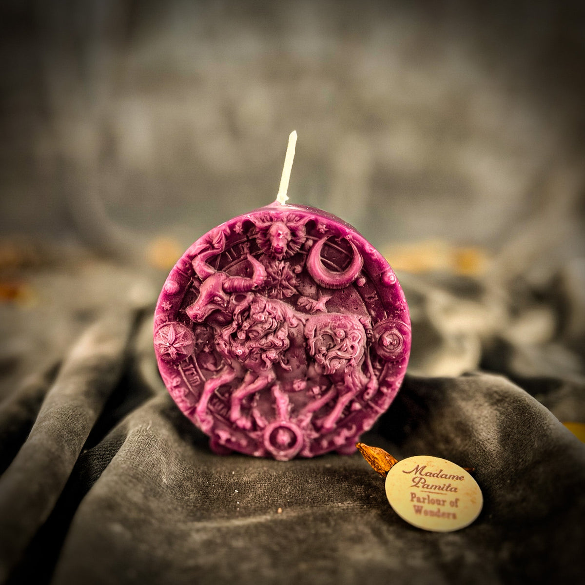Taurus Bull zodiac spell candle in purple on draped gray fabric