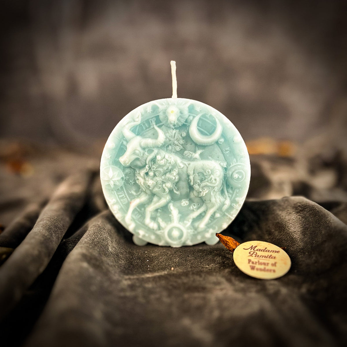 Taurus Bull zodiac spell candle in pale blue on draped gray fabric