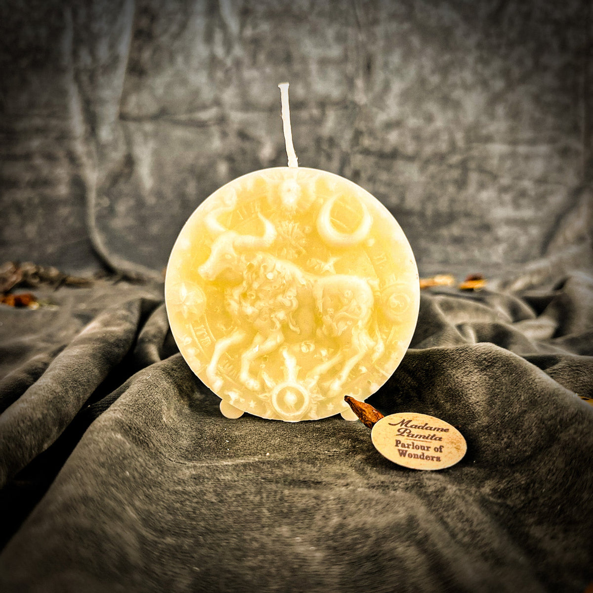 Taurus Bull zodiac spell candle in ivory white on draped gray fabric