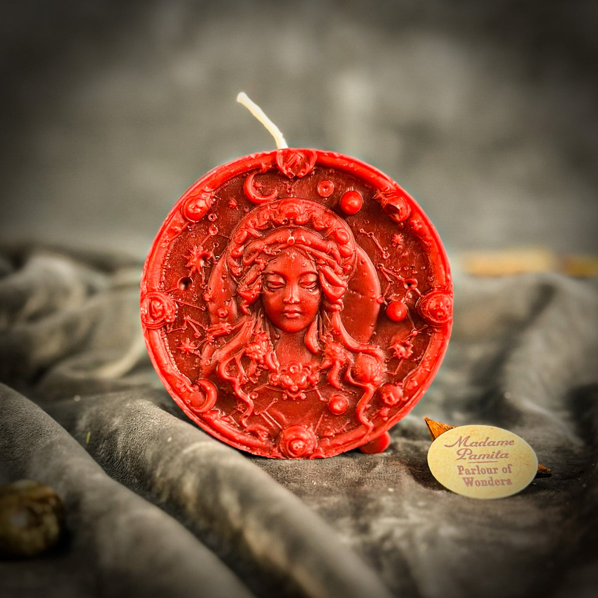 Red Virgo medallion candle on gray velvet, the border of moons and roses clearly visible.