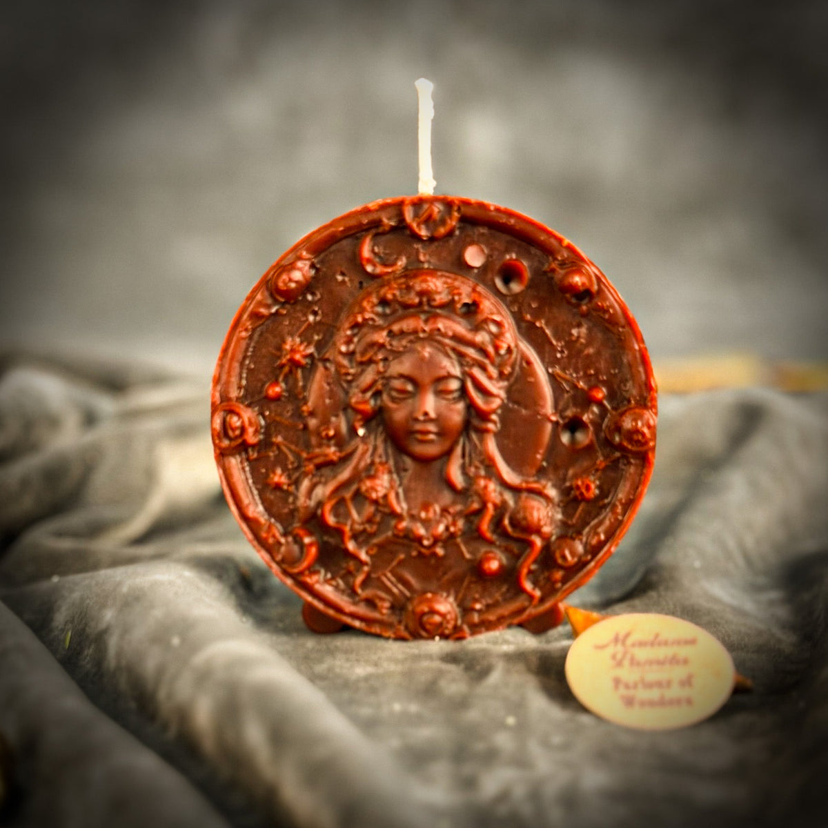 Red-brown Virgo medallion candle standing on its three small feet.