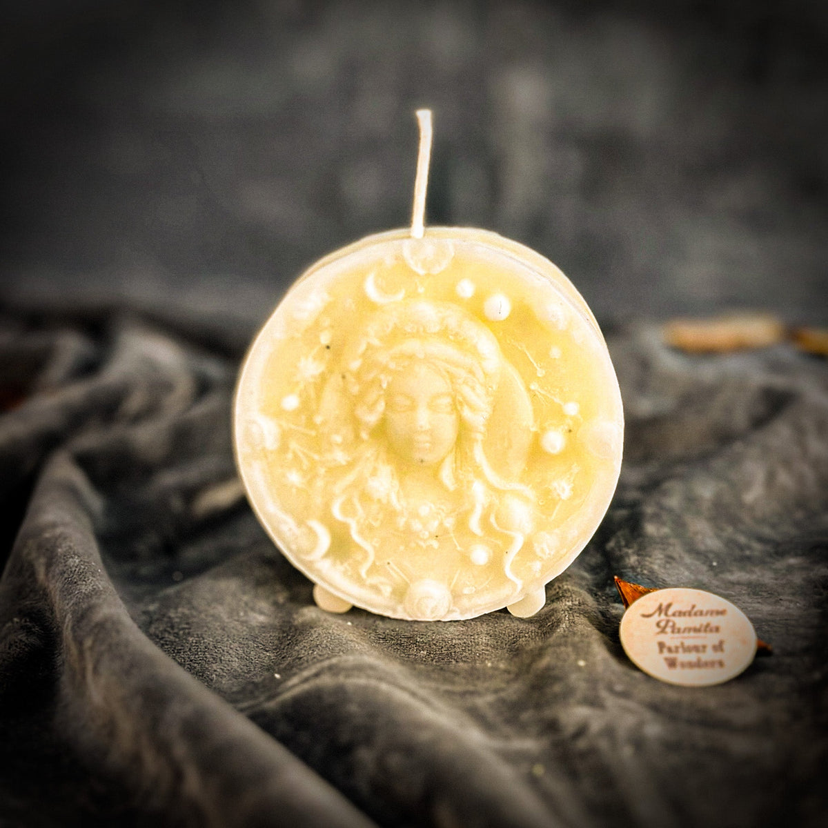 Cream-white Virgo medallion candle with faint specks in the wax.