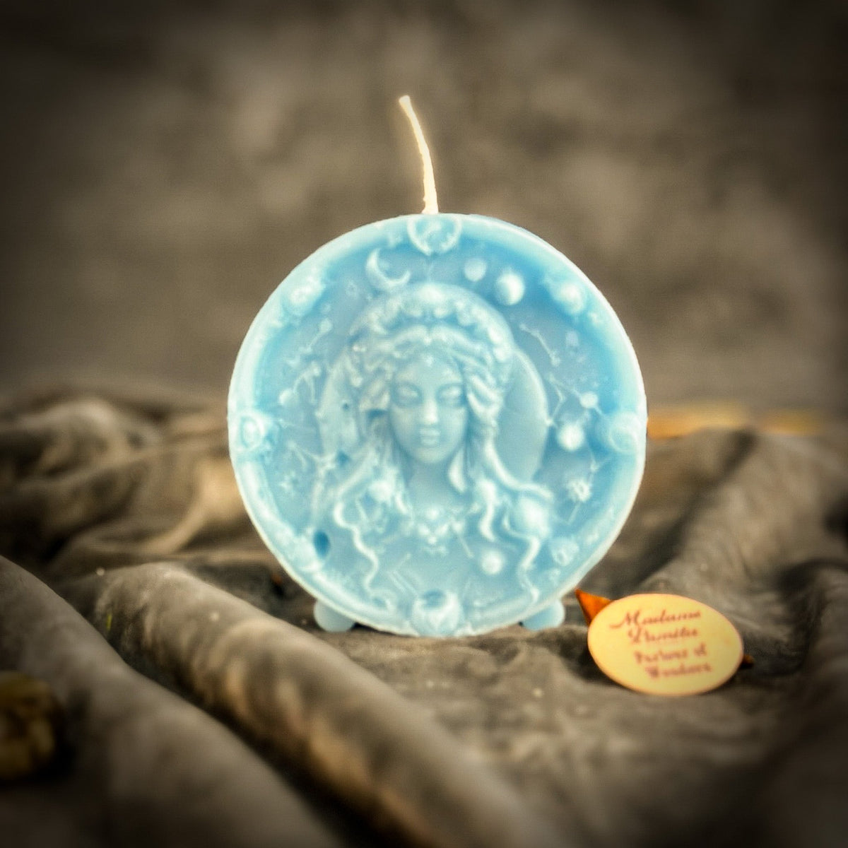 Pale blue Virgo medallion candle, the Maiden's face lighter than the field around it.