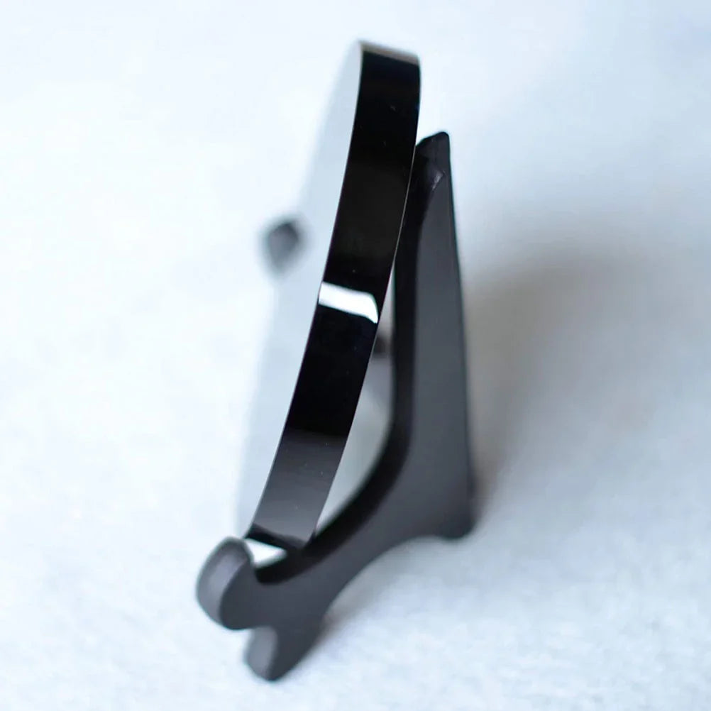 Round polished black obsidian scrying mirror resting on its base stand — view 2 of 11