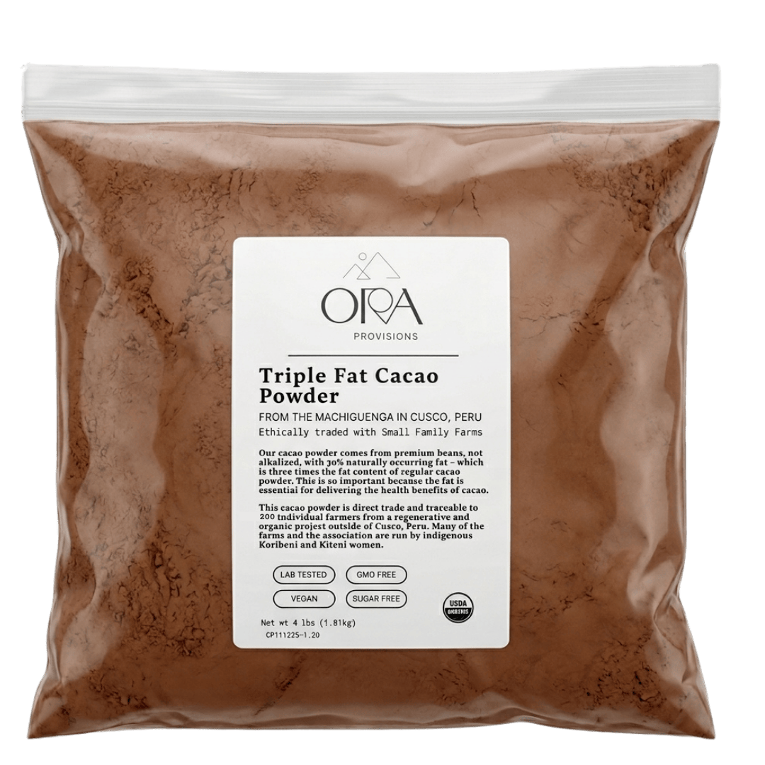 Ora Cacao Triple Fat cacao powder tin arranged in a softly lit lifestyle scene.