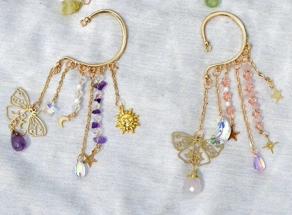 Gold ear cuff earring with sun and moon charms and a long natural quartz crystal drop, worn on one ear