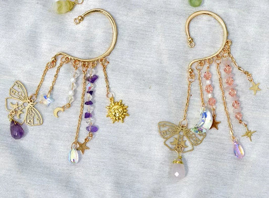 Gold ear cuff earring with sun and moon charms and a long natural quartz crystal drop, worn on one ear