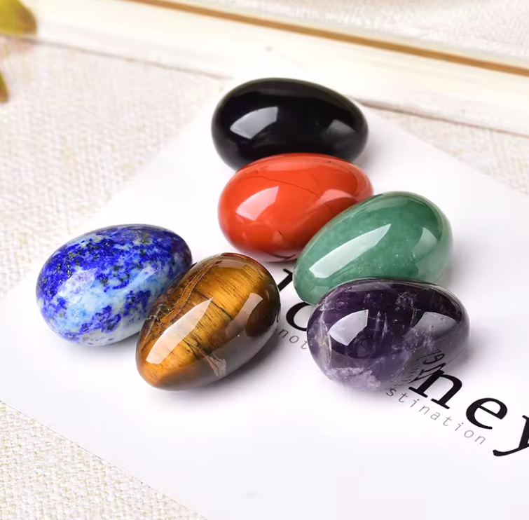 Polished carved crystal egg in assorted gemstones on a dark surface — view 2 of 10