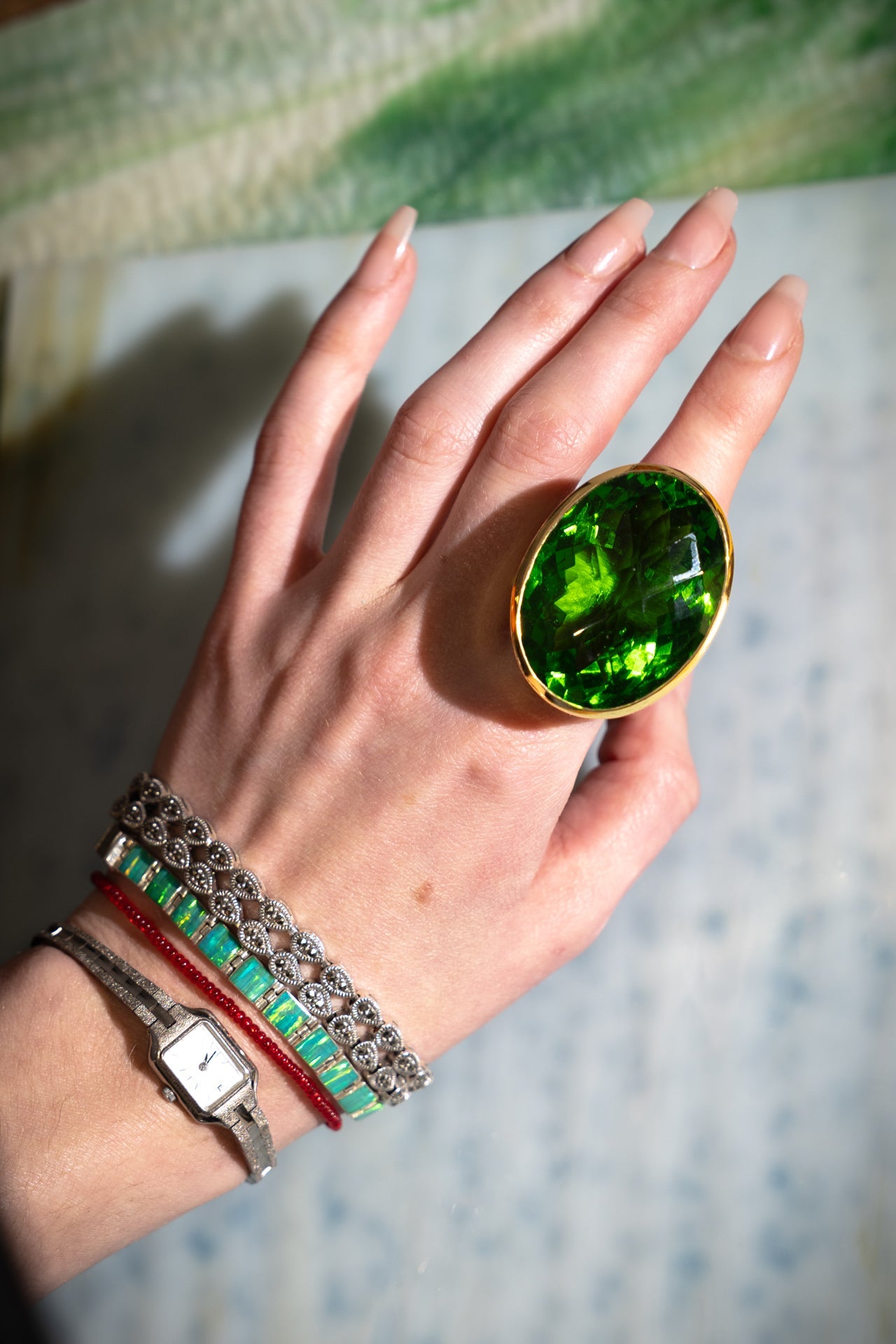 Oval Colossus Ring in Green Envy — oversized faceted green glass oval in a tall gold-plated setting on a wide band