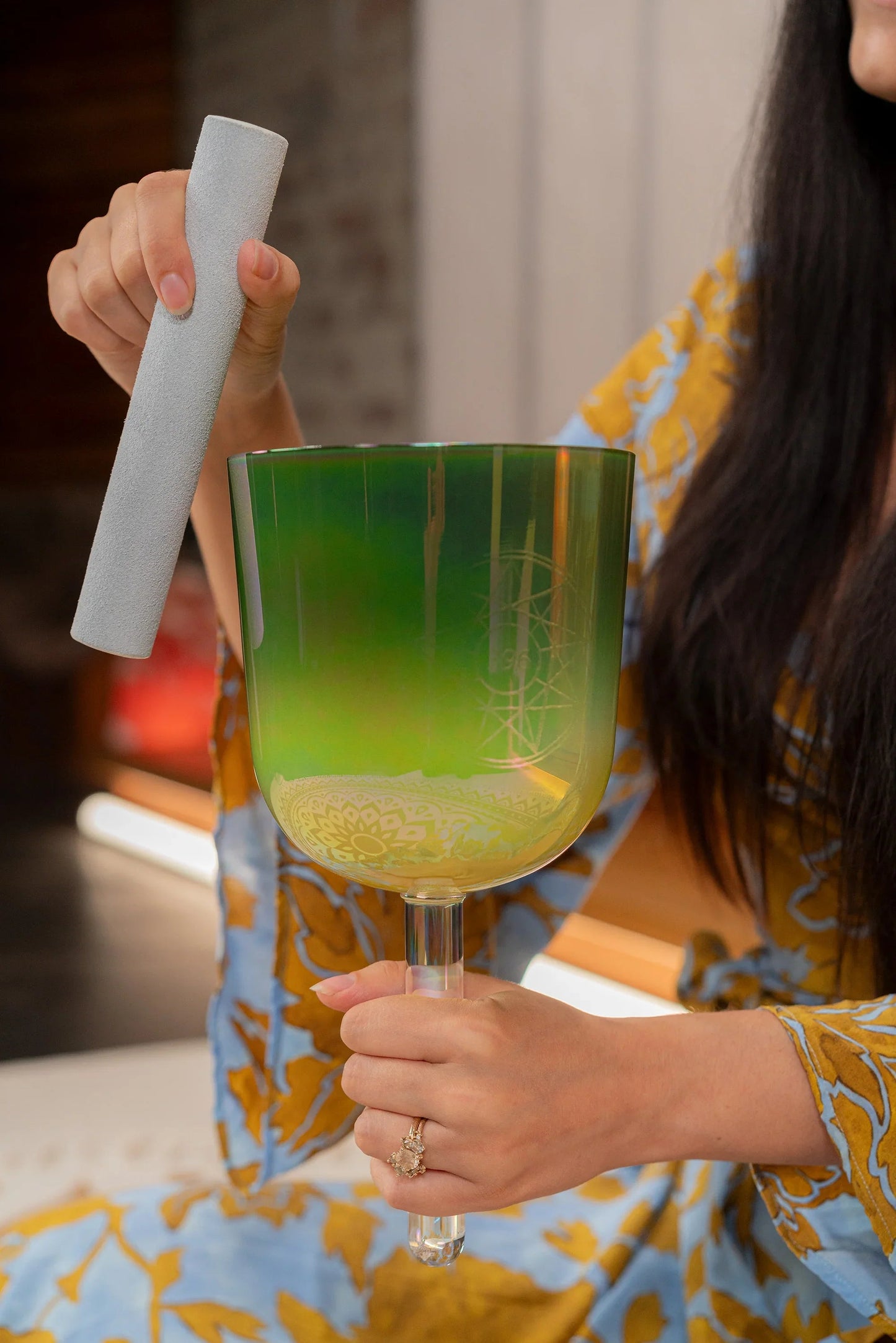 Olive-green frosted crystal singing bowl arranged in a softly lit, styled setting.