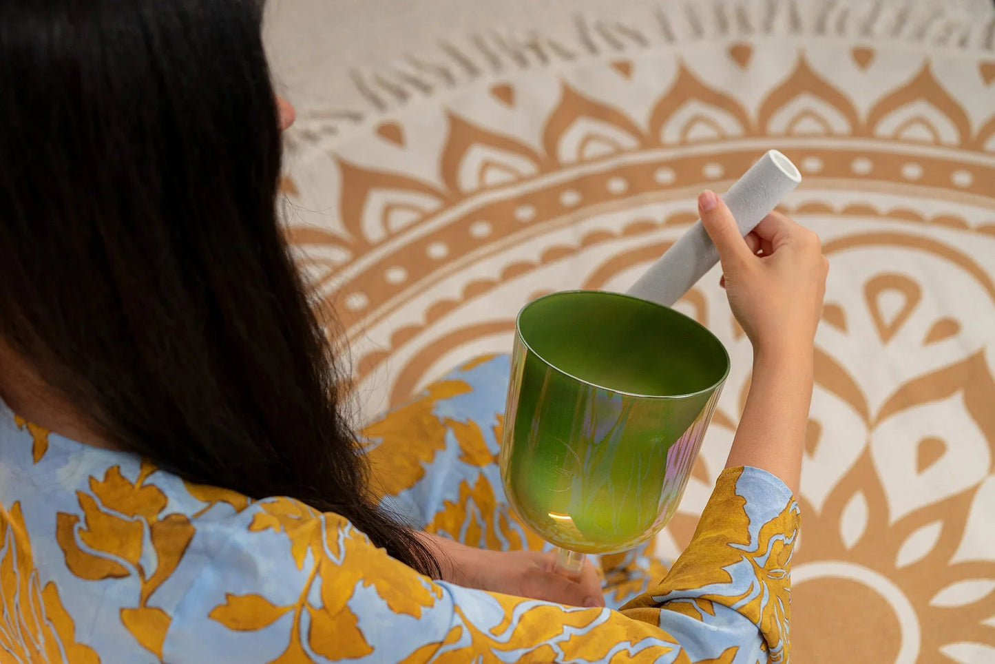 Olive-green crystal singing bowl shown in a warm, styled interior scene.