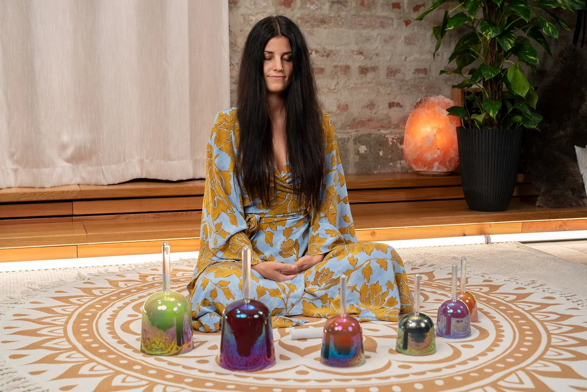 The six-piece set of colored crystal singing bowls shown in a warm, softly lit styled scene.