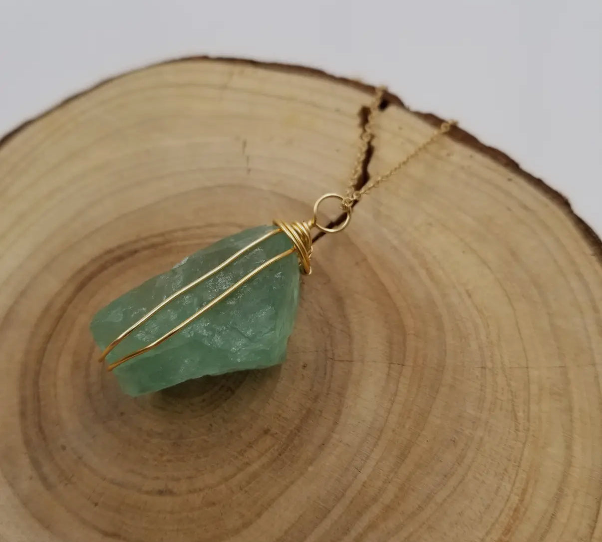The green fluorite pendant hanging from its delicate gold-toned chain.