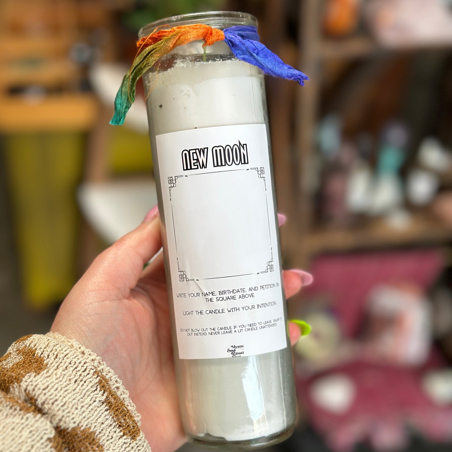 A tall seven-day glass jar candle with a New Moon label.