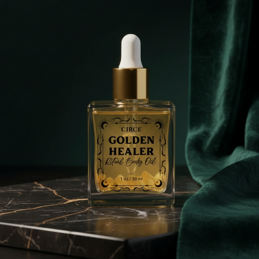 The smaller Golden Healer ritual body oil bottle on dark marble beside green velvet, its cream label reading 'Circe - Golden Healer Ritual Body Oil.'