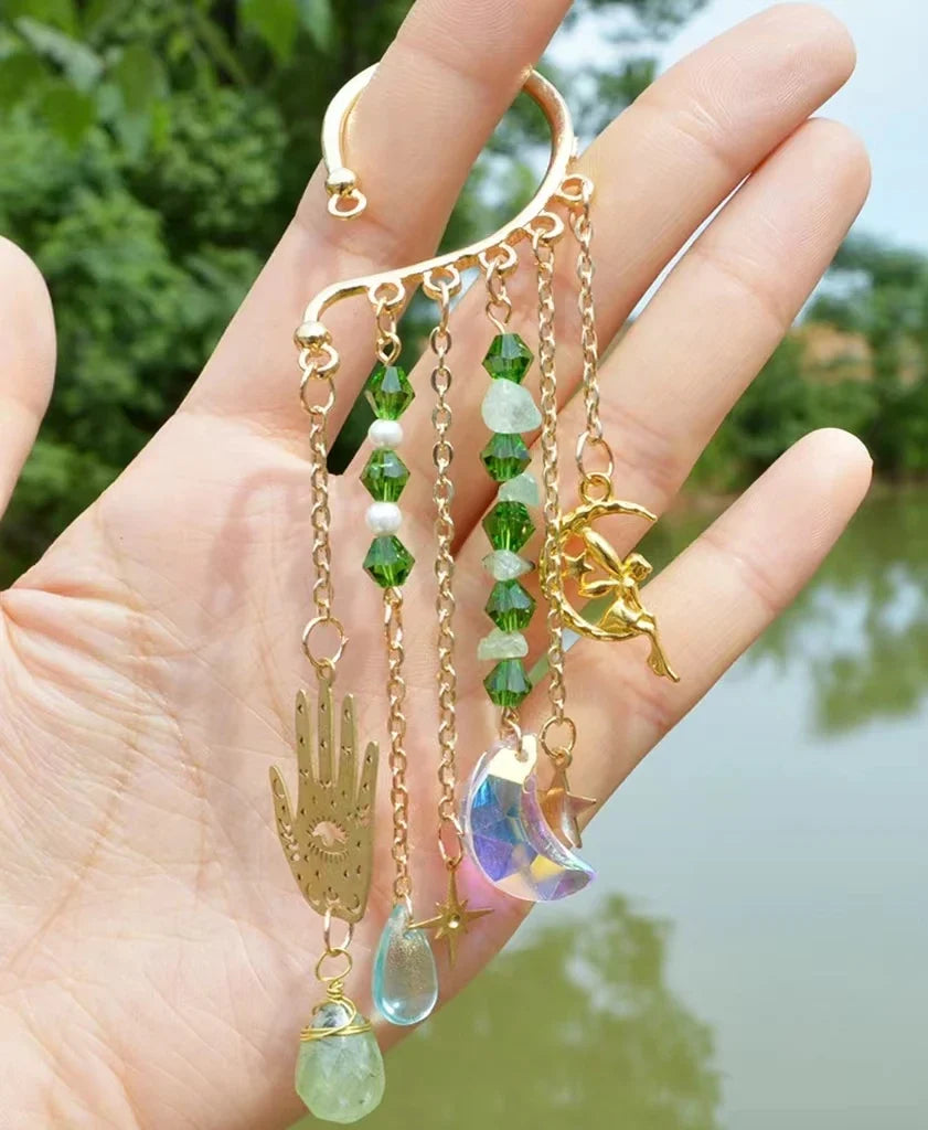 Gold ear cuff earring with sun and moon charms and a long natural quartz crystal drop, worn on one ear — product photo 6