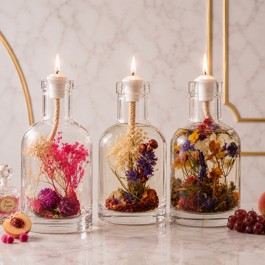 Self-Care Trio: three lit glass oil candles filled with pink, magenta and warm-toned dried flowers, styled on marble with peach slices, red currants and scattered rose petals.