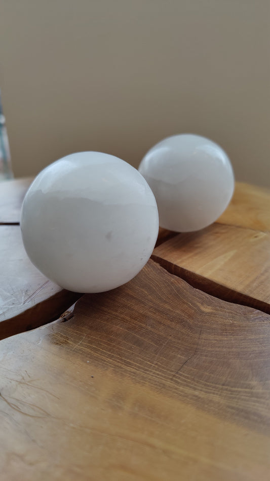 Polished selenite sphere resting on a dark surface