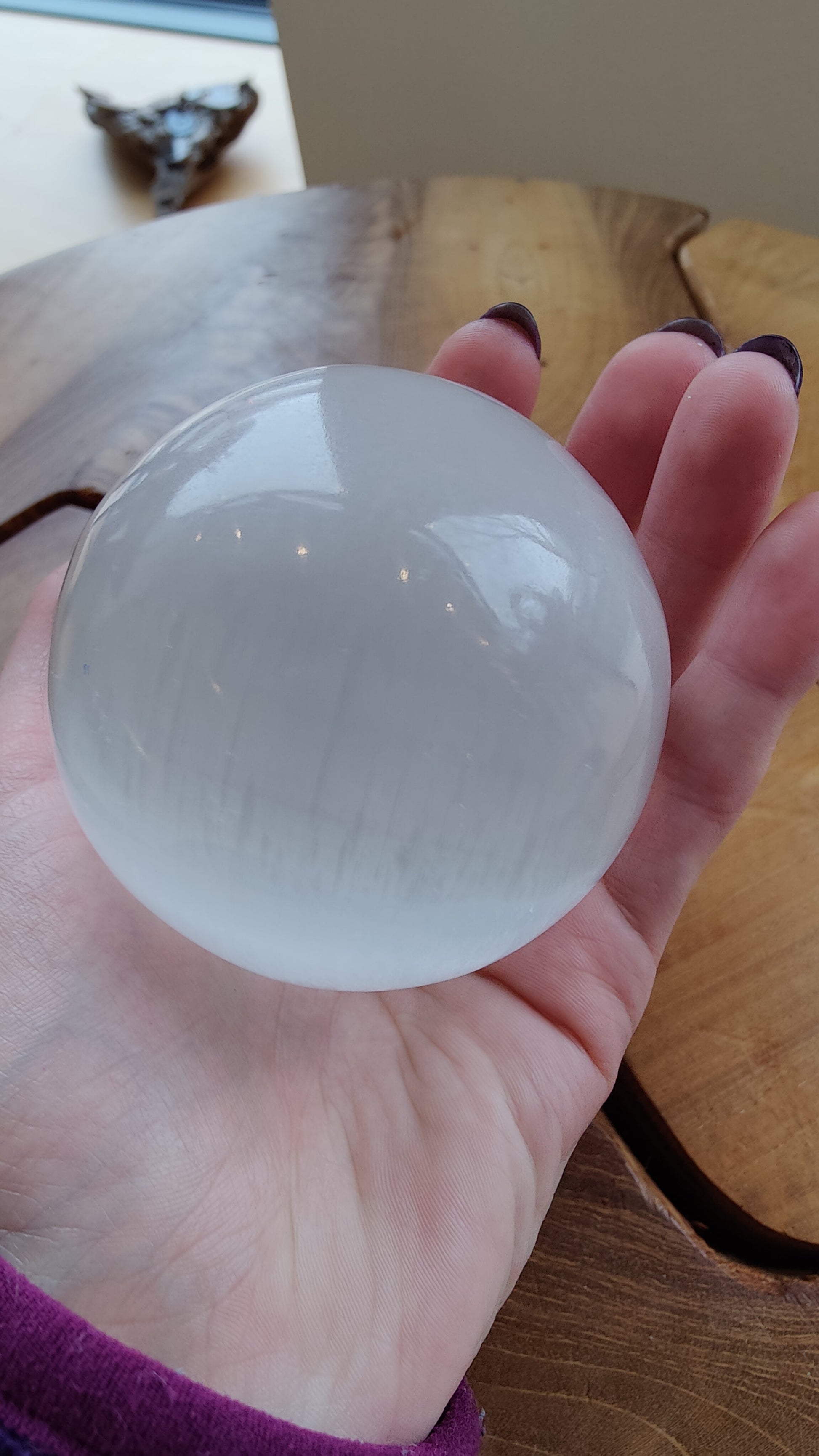 Selenite sphere held in two hands for scale