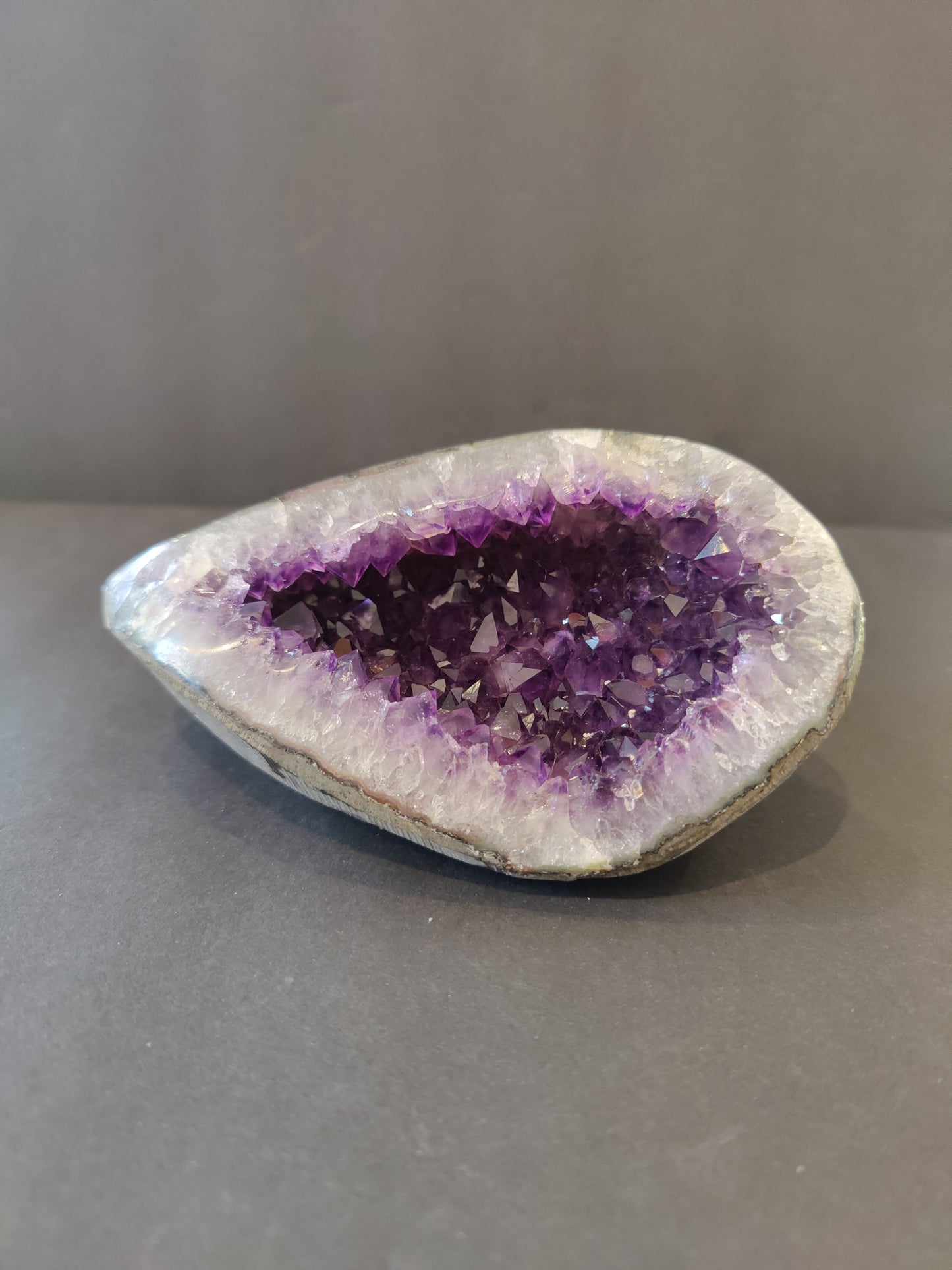 Polished-edge amethyst geode sculpture from Brazil, 6 inches tall, deep purple crystal points inside a grey rind