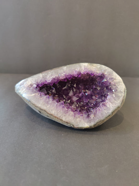 Polished-edge amethyst geode sculpture from Brazil, 6 inches tall, deep purple crystal points inside a grey rind